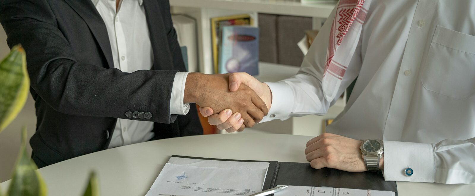 a couple of men shaking hands over a desk