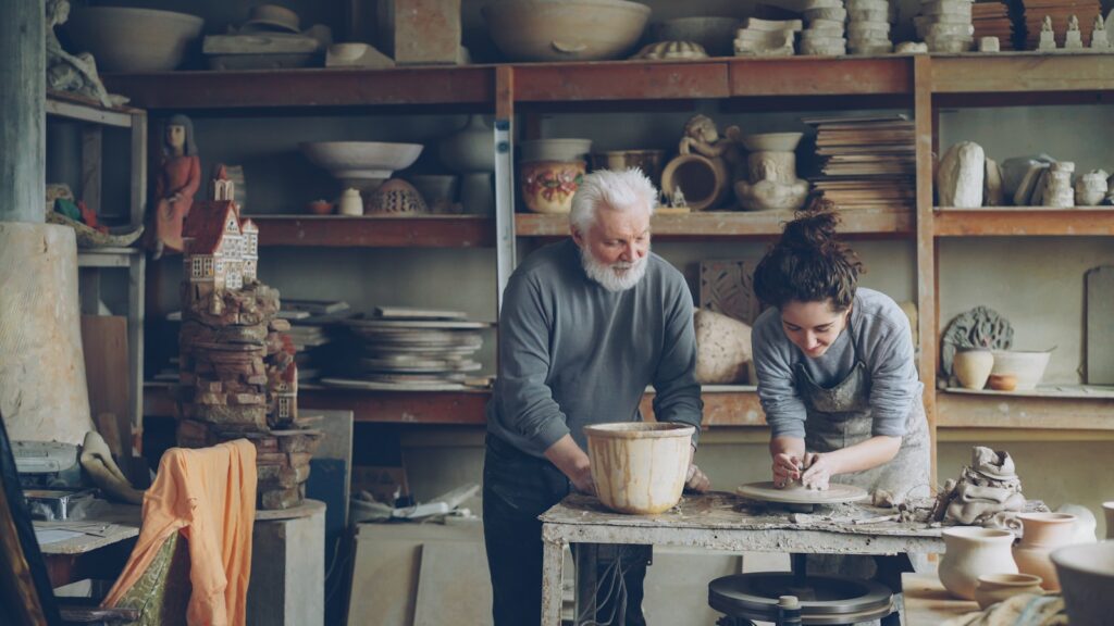 A potter and an apprentice work in a workshop.